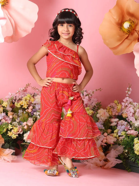 Young girl in a red traditional outfit standing in front of flowers on a pink background