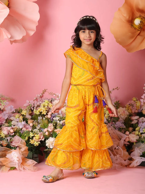 Young girl in a yellow dress standing among flowers with a pink background