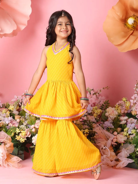 Young girl in a yellow traditional outfit standing among flowers on a pink background
