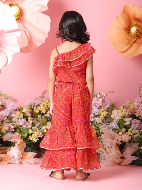 Woman in a red patterned dress standing against a pink floral background