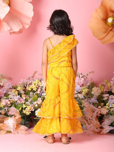Person wearing a yellow dress with floral decorations against a pink background with flowers.