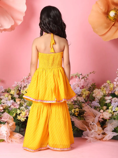 Person wearing a yellow dress with floral decorations on a pink background