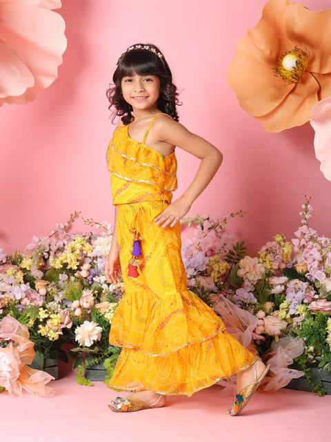Young girl in a yellow dress standing among flowers with a pink background