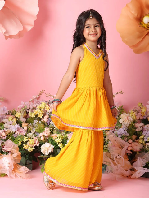 Young girl in a yellow traditional outfit standing among flowers on a pink background