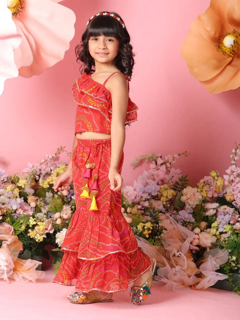 Young girl in a red traditional outfit standing among flowers on a pink background