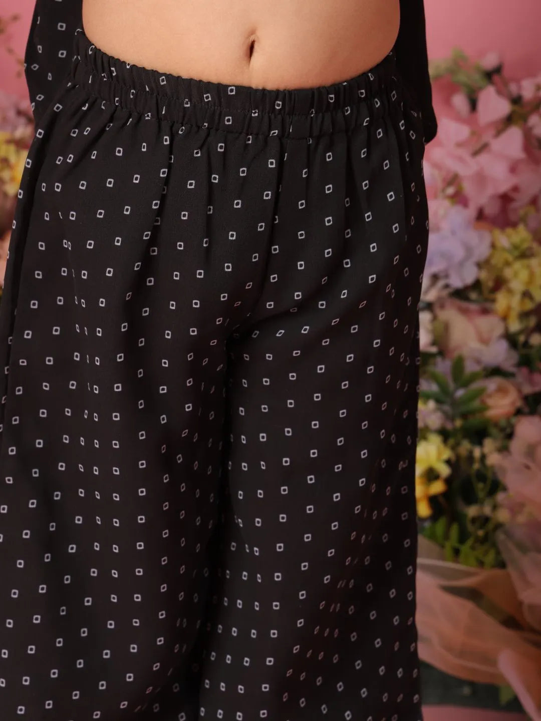 Black patterned pants with a blurred floral background