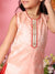 Child wearing a peach-colored sleeveless top with intricate detailing against a pink background