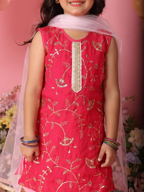 Child wearing a red embroidered dress with a pink floral background