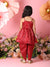 Child wearing a red outfit with floral decorations and flowers in the background