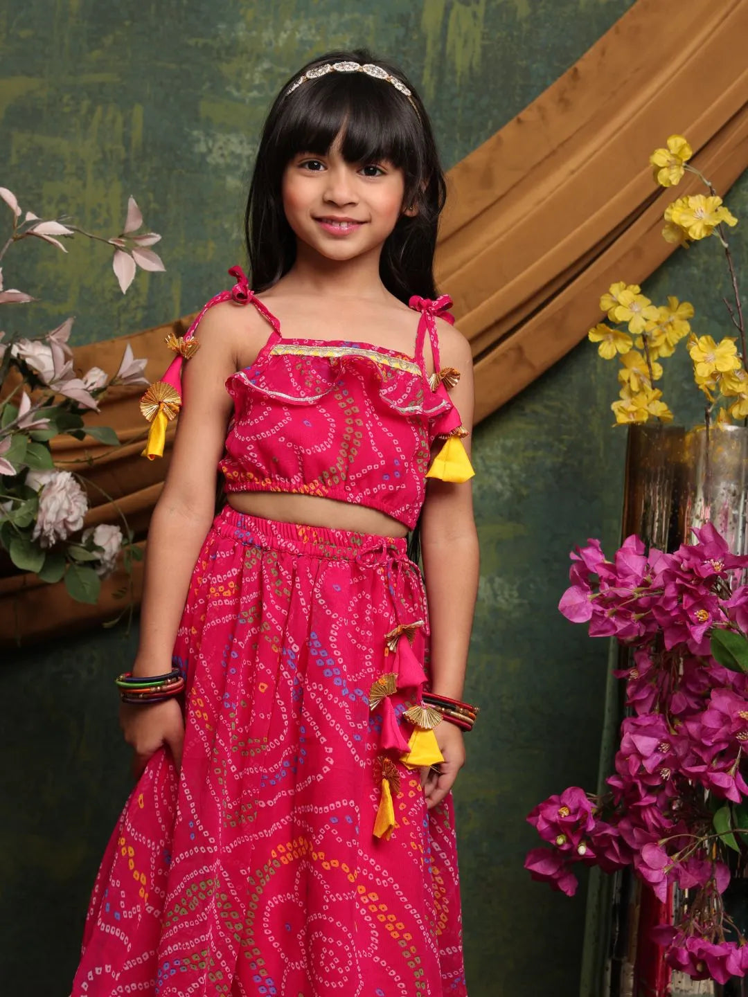 Young girl in a pink traditional outfit standing in front of a floral decorated background