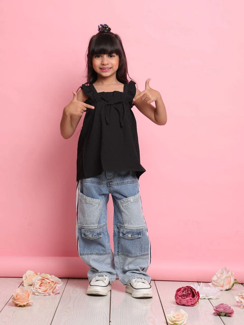 Young girl in black top and blue jeans posing with a pink background