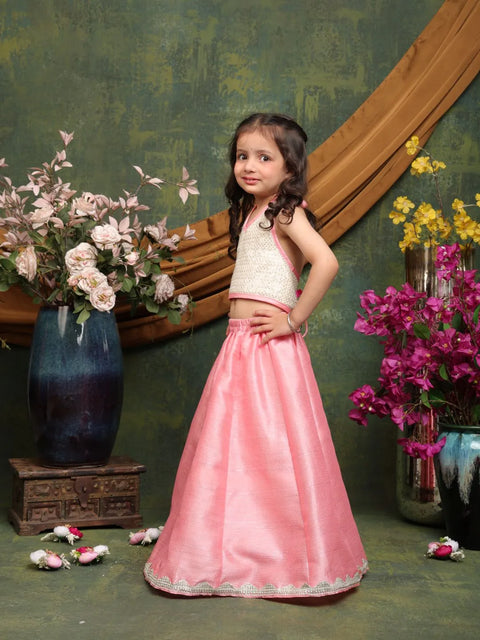 Young girl in a pink skirt standing in front of floral decorations