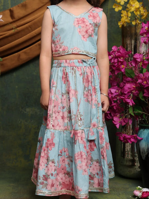 Child wearing a floral dress standing in front of flowers