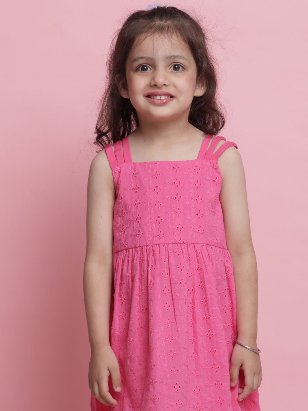 Young girl wearing a pink dress against a pink background