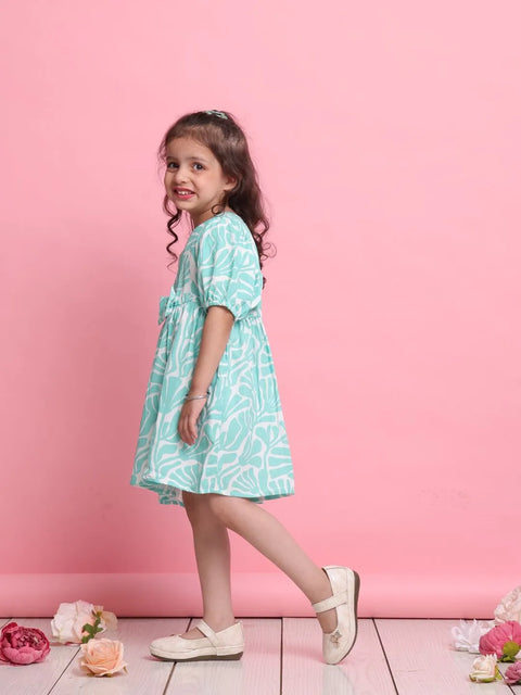 Young girl in a light blue dress standing against a pink background