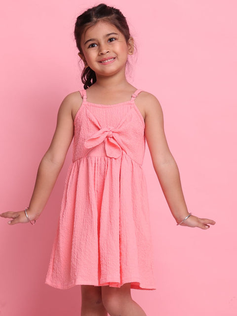 Young girl wearing a pink dress with a bow on a pink background