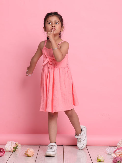 Young girl in a pink dress standing against a pink background