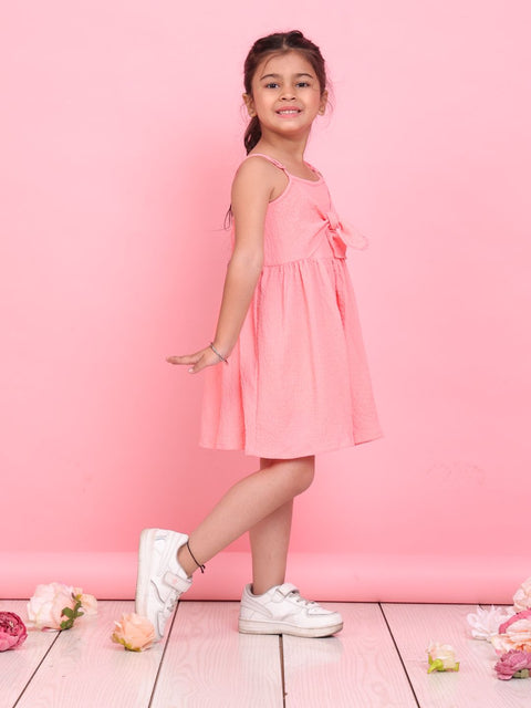 Young girl in a pink dress standing against a pink background