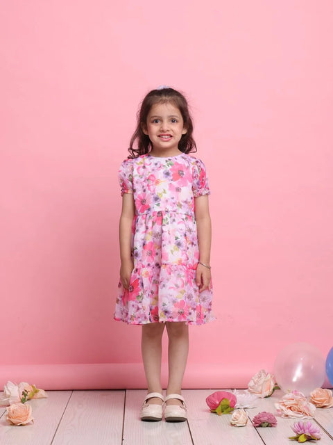 Young girl wearing a floral dress against a pink background