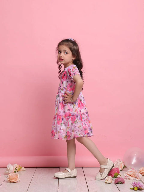Young girl in a floral dress standing against a pink background