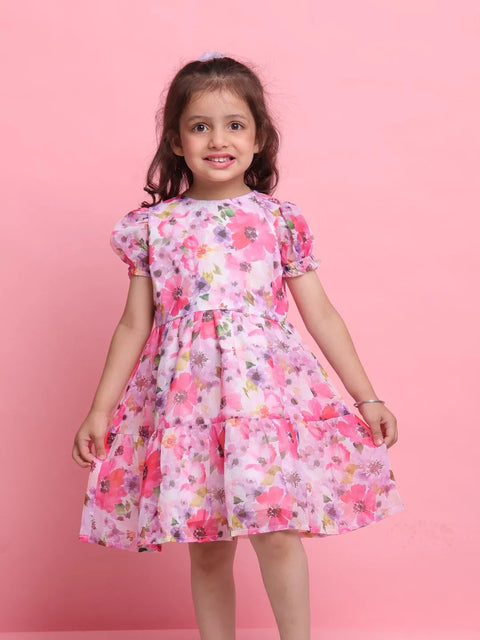 Young girl wearing a floral dress against a pink background