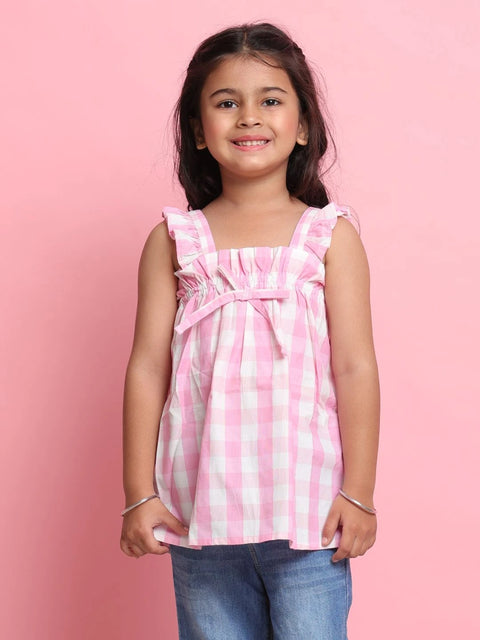 Young girl wearing a pink and white checkered top against a pink background