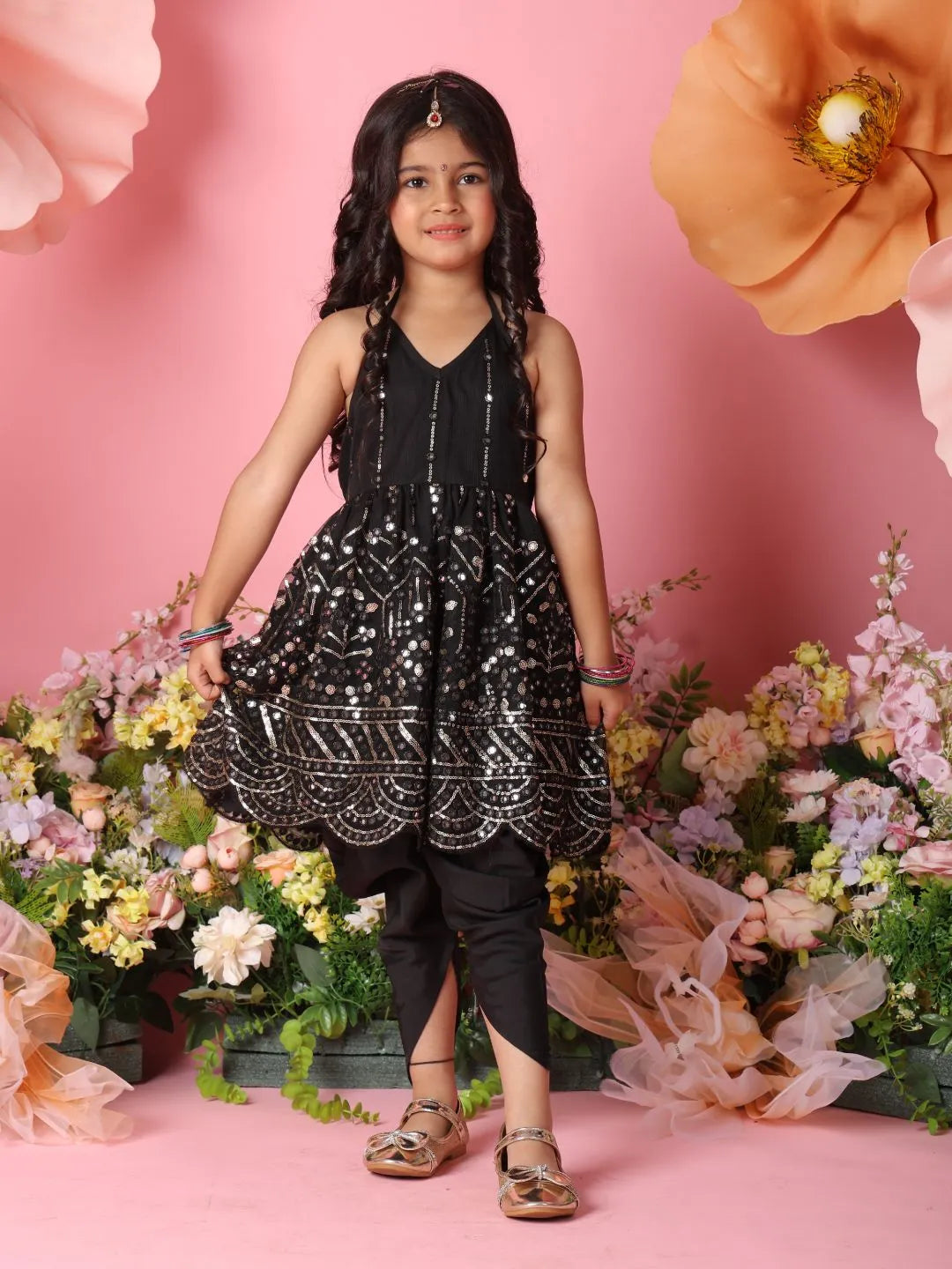 Young girl in a black dress standing in front of pink flowers