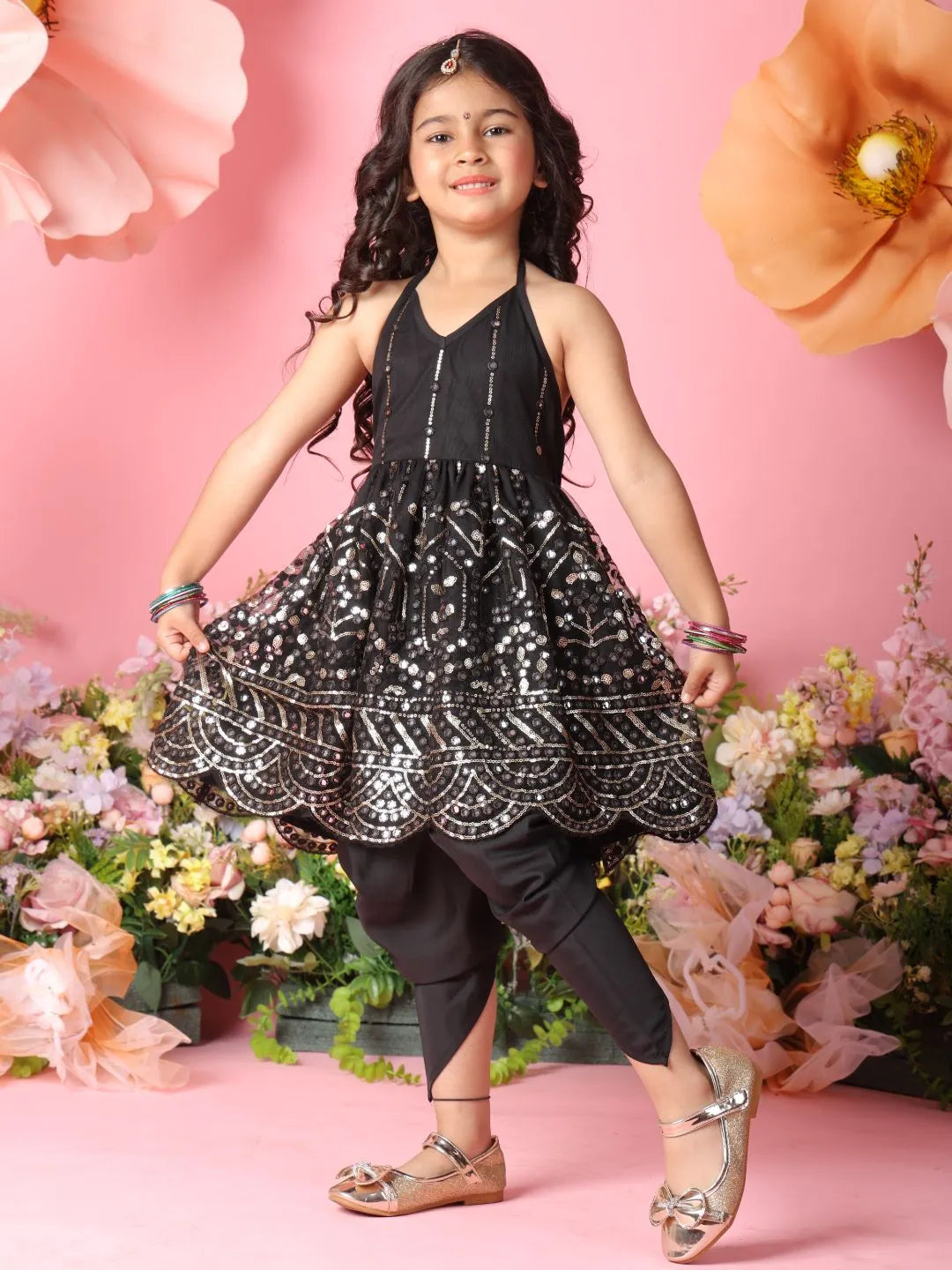 Young girl in a black and white patterned dress standing in front of pink flowers