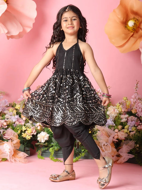 Young girl in a black and white patterned dress standing in front of pink flowers