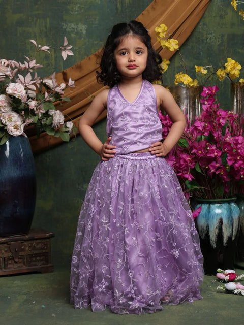 Young girl in a purple dress standing in front of floral decorations