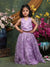 Young girl in a purple dress standing in front of floral decorations