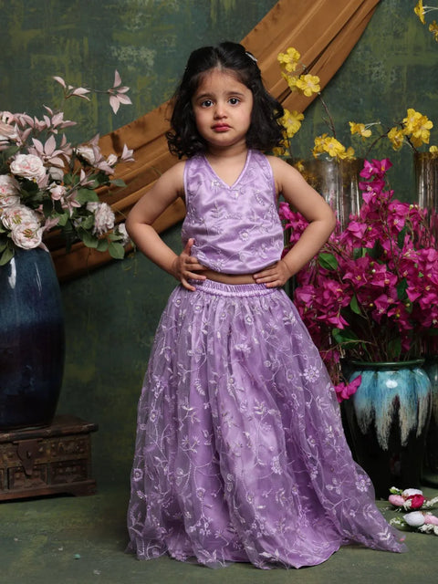 Young girl in a purple dress standing in front of floral decorations