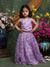 Young girl in a purple dress standing in front of floral decorations