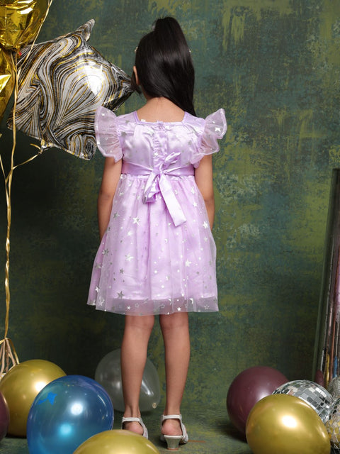 Child in a purple dress standing among balloons against a textured green wall
