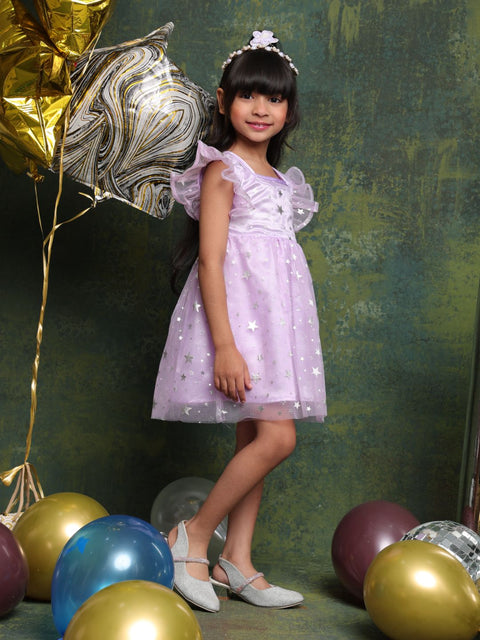 Young girl in a purple dress standing among colorful balloons against a textured green wall.