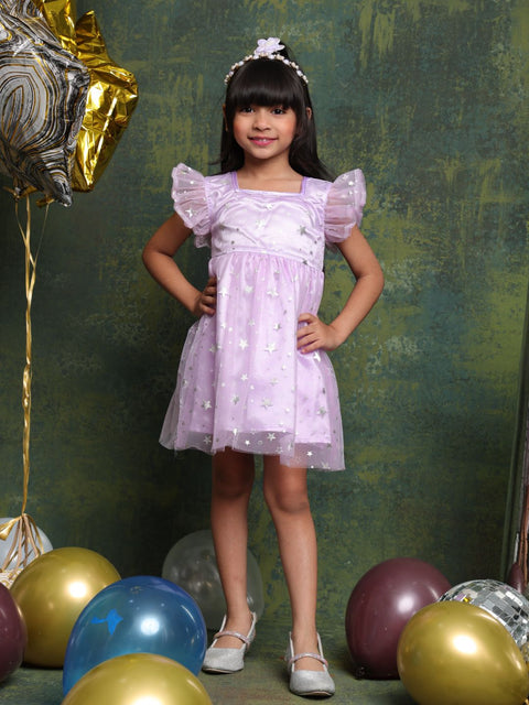 Young girl in a light purple dress standing among colorful balloons against a green textured backdrop