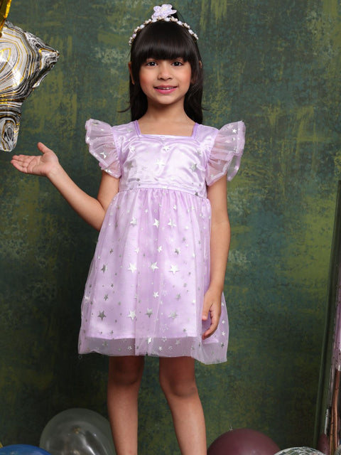 Young girl in a purple dress with star patterns against a textured green wall.