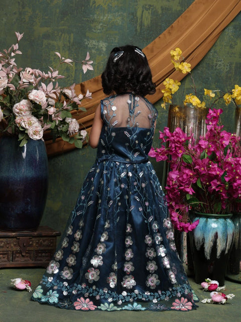 Person in a floral dress standing in front of a decorative wall with flowers and vases.