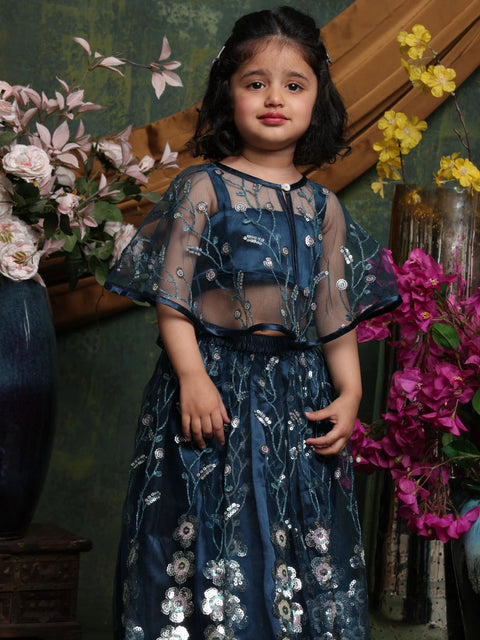 Young girl in a blue embroidered dress standing among flowers