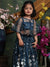 Young girl in a blue embroidered dress standing among flowers