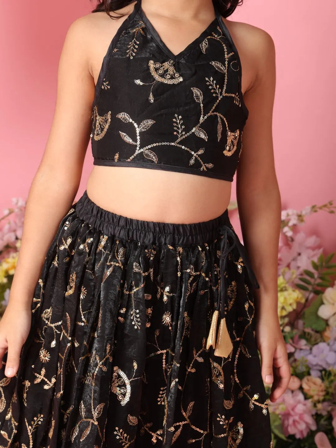 Person wearing a black embroidered top and skirt with a pink floral background