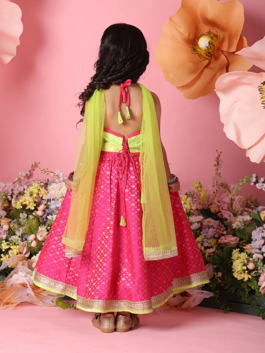 Person wearing a pink and yellow traditional outfit with flowers and pink background