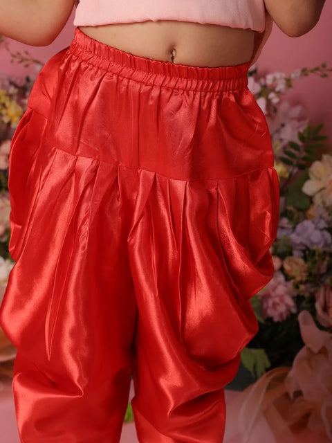 Red satin pants worn by a person with a blurred floral background