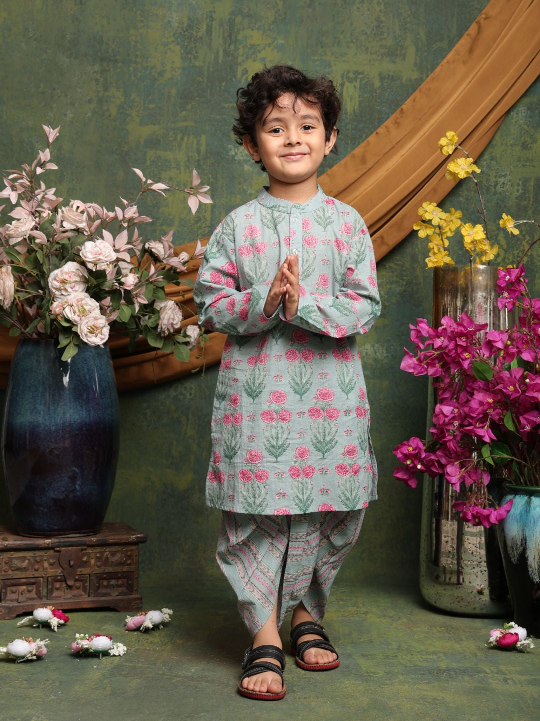 Child in traditional outfit standing in front of floral decorations