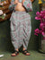 Child wearing a traditional outfit with floral patterns and layered dhoti, standing against a decorative background with flowers.