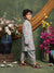 Child in floral outfit standing in a decorative setting with flowers and a mirror.