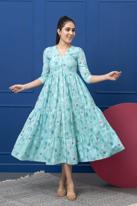 Woman wearing a light blue floral dress against a blue wall.