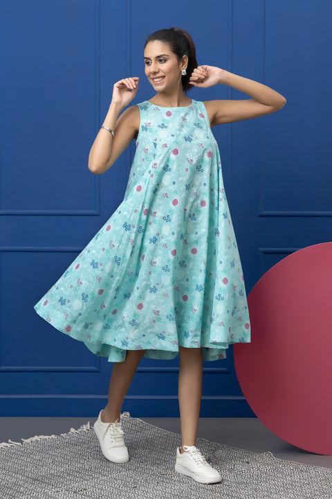 Woman wearing a light blue floral dress against a blue wall with a pink sphere.