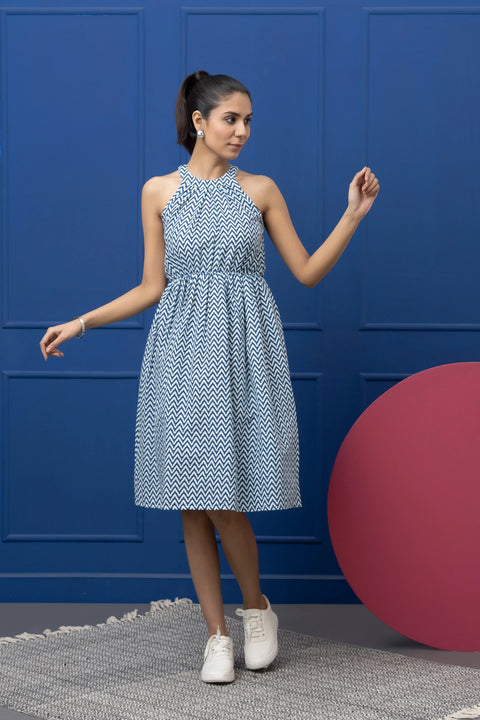 Woman wearing a blue and white patterned dress against a blue wall.