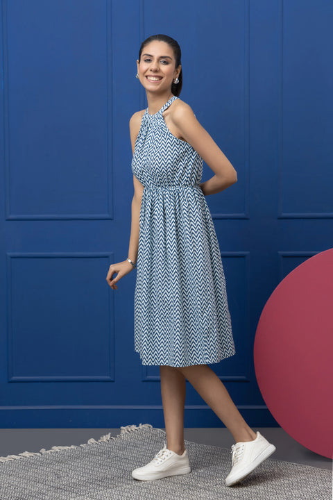 Woman in a blue patterned dress standing against a blue wall with a pink sphere.